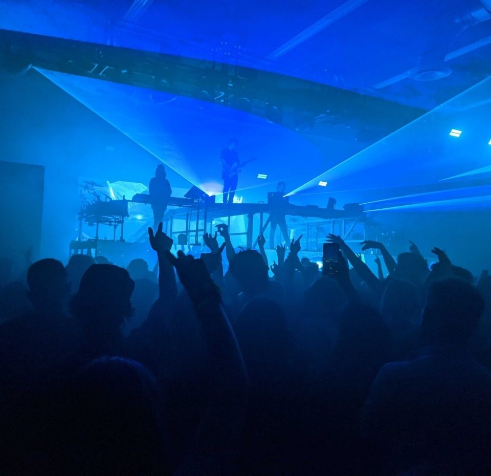 People dancing while band plays a concert in front of blue light beams